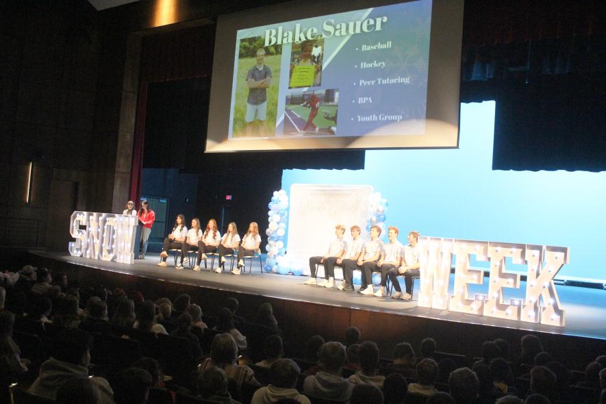 Master of ceremonies Neveah Groen and Izzy Steensma (at podium) finishing announcing the LHS Snow Week candidates Monday afternoon in the school’s performing arts center. Candidates include (from left) Hannah Woodley, Ella Schmuck, Julia Beyer, Anna Banck, Blake Sauer, Jaydon Johnson, Josh Hansen and Connor Bose. Mavis Fodness/Rock County Star Herald Photo