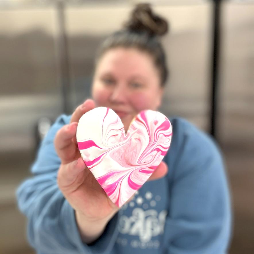 Brittany Loosbrock works on various stages of the jumbo heart-shaped cookies in her B’s Bakehouse kitchen in Luverne.  More than 600 cookies were ordered for the Luv1LuvAll Valentine’s Day fundraiser. Submitted photo