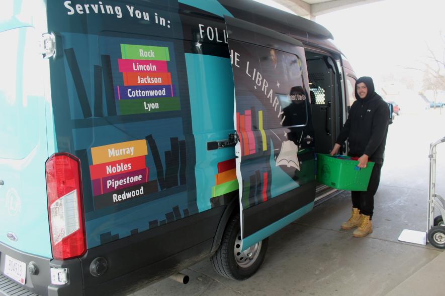 Eric Bierman, carrier driver with Plum Creek Library System (PCLS), delivers requested materials Friday morning to the Rock County Library in Luverne. The PCLS recently purchased the 2025 Ford cargo van brightly wrapped in a vehicle graphic from Quality Printing in Luverne. Mavis Fodness/Rock County Star Herald Photo
