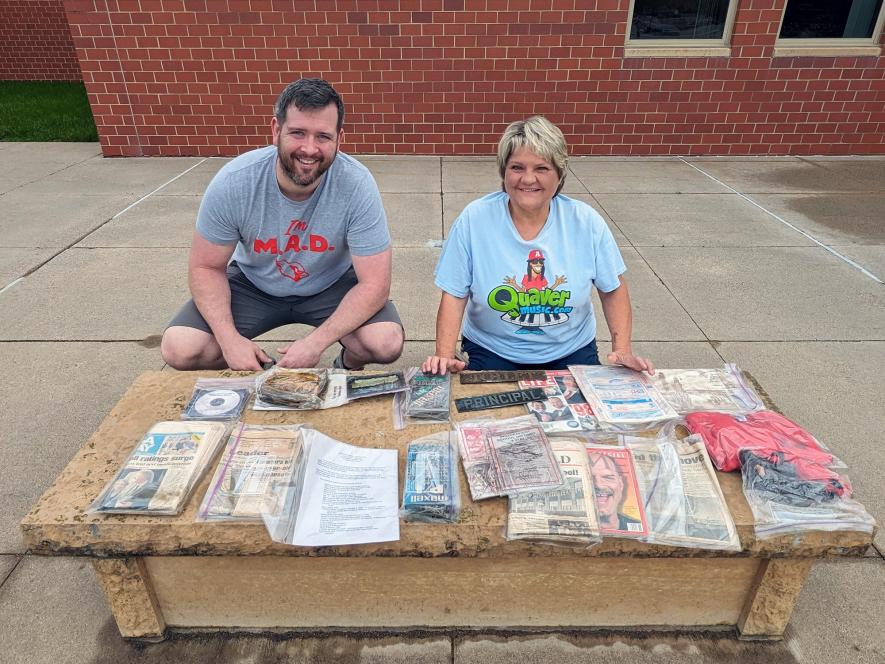 Britton Stratton (left) and Beth Capistran pose with the materials placed in the time capsule when the current Luverne Elementary School opened in November 1998. Stratton was a kindergartner 25 years ago and Capistran has been a music teacher until her retirement this year. Most of the materials sealed in a plastic tub and placed in the stone bench were ruined by moisture. Submitted Photo