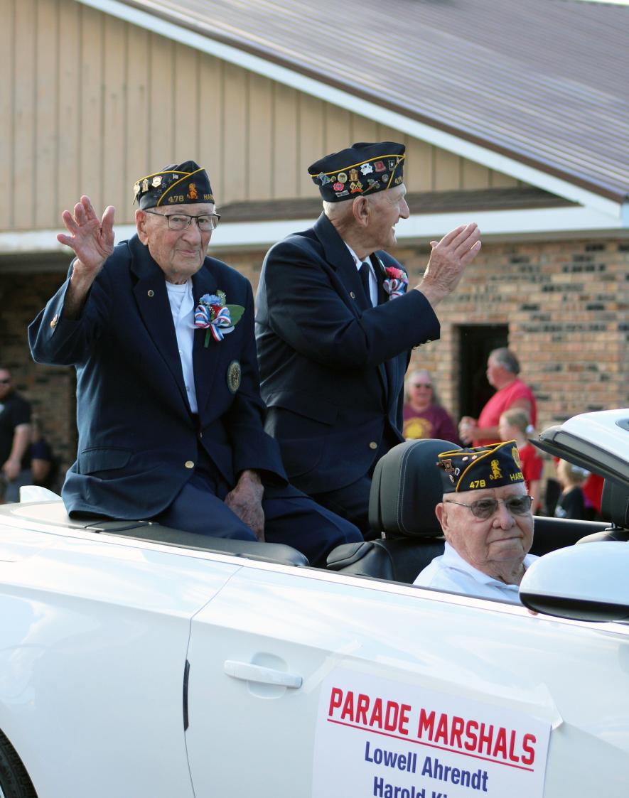 Parade marshals (from left) Russell Wenzel, Lowell Ahrendt and Harold Kindt wave to the crowds lining Main Street in Hardwick Saturday night for the annual Jubilee Days parade. All three served in the Korean War and became members of the Hardwick American Legion Post No. 478 when the post was organized in 1957. After their military service, each maintained longtime connections to the Hardwick community. Mavis Fodness/Rock County Star Herald Photo