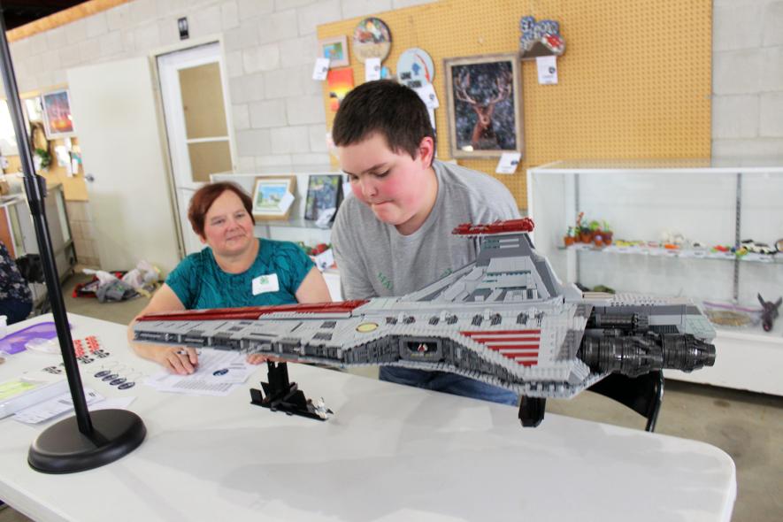 After putting in 100 hours assembling his Lego project, 4-H’er Eliot Cauwels carefully lifts his craft project off the judge’s tableHe told judge Nancy Ihrke Monday he spread the assembly over two months. Mavis Fodness/Rock County Star Herald Photo