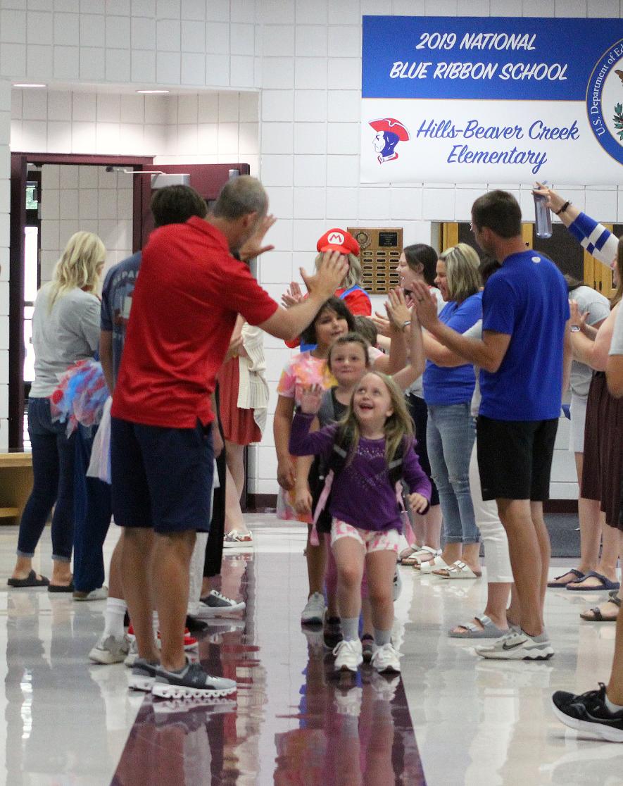 Lucy Lynde gives teacher Rex Metzger a high-five followed by Brooke Kellenberger and Ava Anderson Tuesday morning at Hills-Beaver Creek Elementary School. The teachers and staff formed a tunnel to greet students to the first day of the 2023-24 school year. Rock County Star Herald Photo/Mavis Fodness