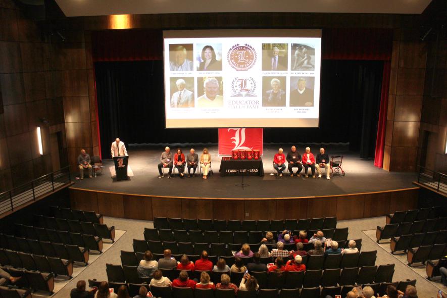 Luverne Public Schools Superintendent Craig Oftedahl (far left, at podium) introduces the Class of 2025 Alumni and Educator Halls of Fame inductees Friday afternoon in the performing arts center. On stage (from left) are Luverne School Board member and award presenter Mike DeBates, Tim Connell, Dyan Ebert, David Piepgras, Mao Wildung, Laurin Carroll, Gregg Gropel, Katie Hemme and Joseph Roberts. Mavis Fodness/Rock County Star Herald Photo
