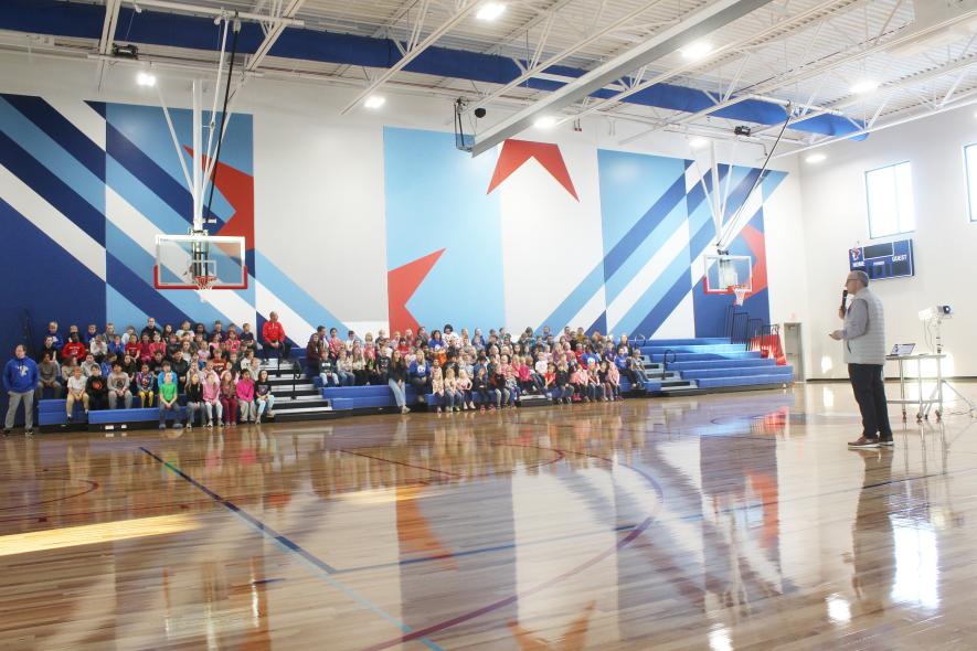 Hills-Beaver Creek Elementary School Principal Todd Holthaus (far right) talks with the kindergarten through fifth-grade students and staff during an assembly in the gymnasium at the new elementary school, which opened Monday. Mavis Fodness/Rock County Star Herald Photo