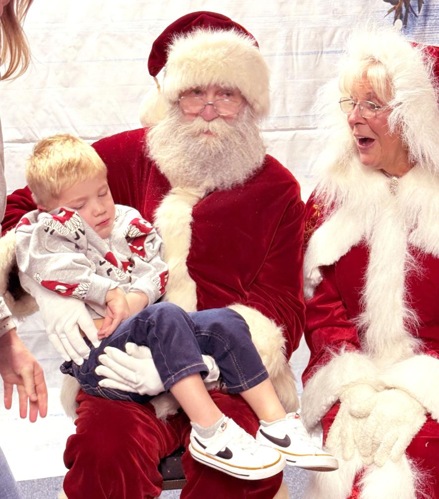 A sleeping Jayden Haraldson has his picture taken with Santa and Mrs. Claus. Photo courtesy of Hardwick Community Club