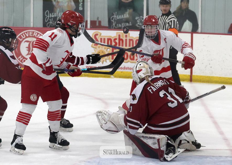 Greg Hoogeveen photo/GHOCFM3 Luverne sophomore Ellie Van Batavia, No. 11, and senior Greta McClure, No. 15, try to get their sticks on the puck above the Fairmont goalie Saturday, Feb. 7, in Luverne. LHS beat Fairmont 5-2 in section 3 semifinal action.