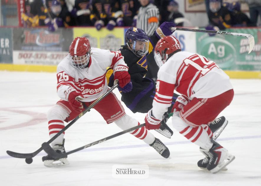 LHS senior Jude Hoven, No. 26, and junior Rick Rogers, No. 14, knock a Rochester player off the puck as he crosses the blue line. Luverne beat the Lourdes 3-2 in the first game of the season Saturday, Nov. 22, at home.