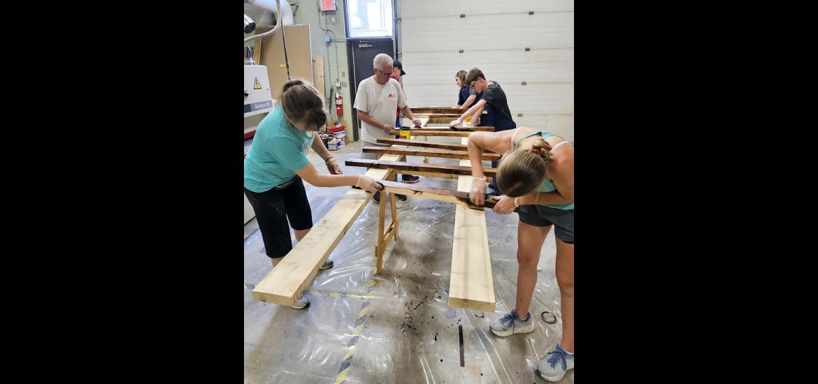 Volunteers (from left) Holly Wessels, Scott Wessels, Elijah Henrichs, Leah Mueller, Brendan Snyders and Reagan Gangestad stain wood pieces Monday afternoon that will be assembled into beds for the “Sweet Dreams” initiative. Jason Berghorst/Rock County Star Herald Photo