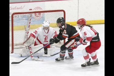 Sophomore Luverne goalie Emma Saarloos, No. 30, blocks a Marshall shot as freshman Macie Edstrom, No. 16, looks to knock the puck away from the front of the goal. Marshall beat Luverne 5-2 Thursday, Jan. 25, in Luverne.