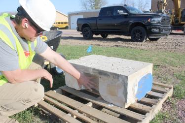 Brad McColley with the Litchfield-based demolition company DRC places his hand where he excavated a time capsule inside an unknown cornerstone from the former Hills High School on April 15. The time capsule, a sealed 4-by-6-inch metal box will be open by school district officials at a later date. Mavis Fodness/Rock County Star Herald Photo