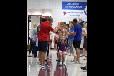Lucy Lynde gives teacher Rex Metzger a high-five followed by Brooke Kellenberger and Ava Anderson Tuesday morning at Hills-Beaver Creek Elementary School. The teachers and staff formed a tunnel to greet students to the first day of the 2023-24 school year. Rock County Star Herald Photo/Mavis Fodness