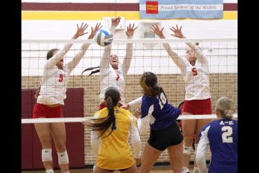 Junior Payton Behr (left), junior Amira Cowell and senior Tori Serie team up to block a shot from Adrian-Ellsworth Thursday, Sept. 14, in Ellsworth. The Dragons won the match in three sets.