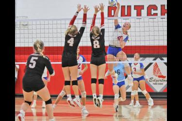 Freshman Brynn Bakken rises above the net to spike the ball against two Edgerton defenders. The Patriots lost the “Queens of the Court” three sets to one on Friday, Sept. 22, on the road.