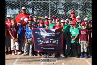 Brian Weber (back, left) and Barry Shelton (back, right) from the Luverne Baseball Association, stand with several team players presenting a banner from the Twins Fields for Kids Grant Program Tuesday, June 11, at Joe Roberts Field. 