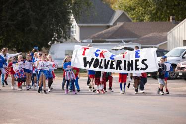 H-BC Elementary students brought a large banner, “Tackle the Wolverines,” and held smaller placards to encourage a football win on their walk in the Homecoming parade. Samantha McGaffee/Rock County Star Herald Photo